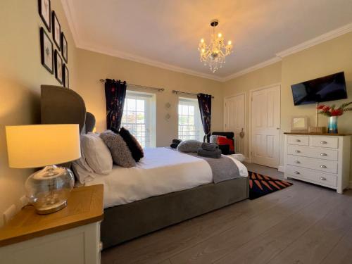 a bedroom with a large bed and a chandelier at May Bell Cottage in Dersingham