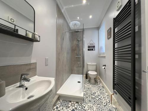 a bathroom with a sink and a shower and a toilet at May Bell Cottage in Dersingham