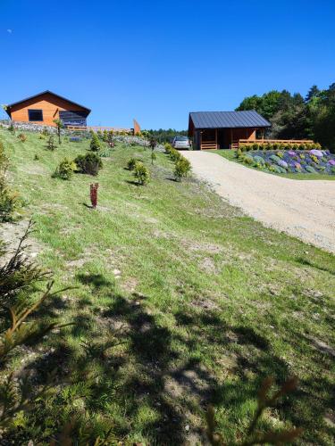 a grassy hill with a house in the background at ROZTOCZE, Domek Na Leśnym Wzgórzu, Zwierzyniec, Krasnobród,Zamość in AdamÃ³w