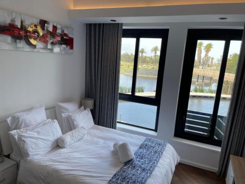 a bedroom with a white bed and a large window at Bridgewater one luxury Apartment in Cape Town
