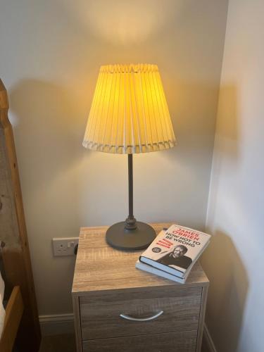 una mesa con una lámpara y un libro sobre ella en Cosy double room with private bathroom homestay, en Caldecote