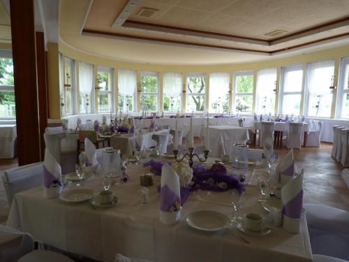 a room filled with tables with white tablecloths and chairs at Waldhaus Colditz Garni in Colditz