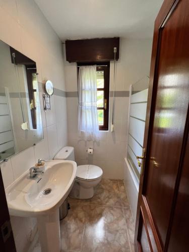 baño con lavabo y aseo y ventana en Hostal La Ruta, en Caín