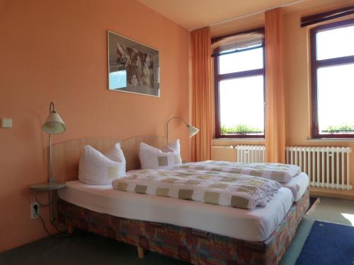 a bedroom with a large bed with two windows at Waldhaus Colditz Garni in Colditz