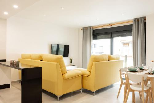 a living room with two yellow chairs and a table at Apartamentos Kouohana in Fuengirola