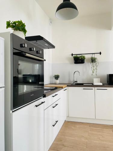 La cuisine est équipée de placards blancs et d'un four avec plaques de cuisson noires. dans l'établissement BE MY APPARTS, Appartement de charme 