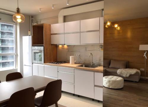 a kitchen with white cabinets and a table with chairs at Квартира в Авалон на вулиці Чорновола 16є новобудова in Lviv