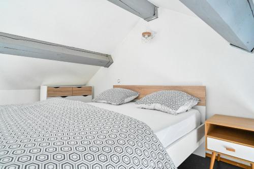 een witte slaapkamer met een bed en 2 kussens bij Jolie appartement climatisé in La Ciotat