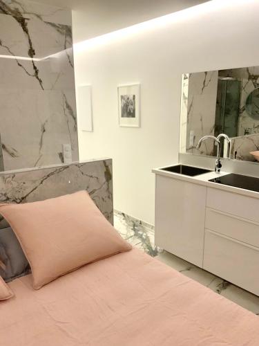 une chambre avec un lit, un lavabo et un miroir dans l'établissement Caraïbes Heliopolis naturiste, au Cap d'Agde