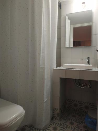 a bathroom with a white shower curtain and a sink at Elthimia's apartment in Poros