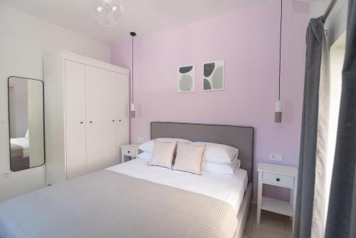 een witte slaapkamer met een bed met 2 kussens bij Antheon apartments in Vathi