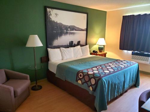 a hotel room with a bed with a painting on the wall at Super 8 by Wyndham Ticonderoga in Ticonderoga