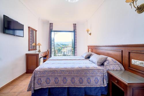 
a bedroom with a large bed and a large window at Hotel Villa Frigiliana in Frigiliana
