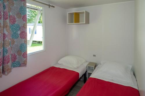 deux lits dans une chambre avec une fenêtre dans l'établissement Camping du Bournat, au Bugue