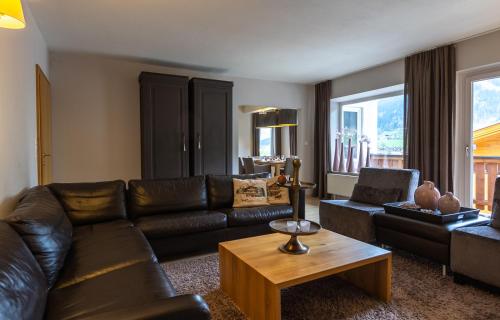 a living room with a leather couch and a table at Haus Almkreek in Kaprun