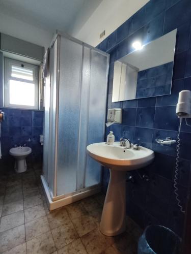 a blue tiled bathroom with a sink and a shower at Hotel Il Dollaro in Villa San Giovanni