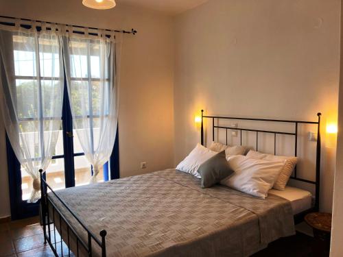a bedroom with a bed and a large window at Andros Studios Tetrafylli in Andros