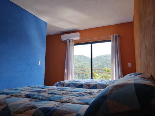 1 dormitorio con 2 camas y ventana en Hotel El Mirador, en Xilitla