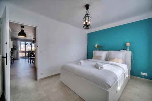a bedroom with a large white bed with a blue wall at IMMOGROOM - Renovated - Loggia - Clear view - Parking common - AC - Wifi in Cannes
