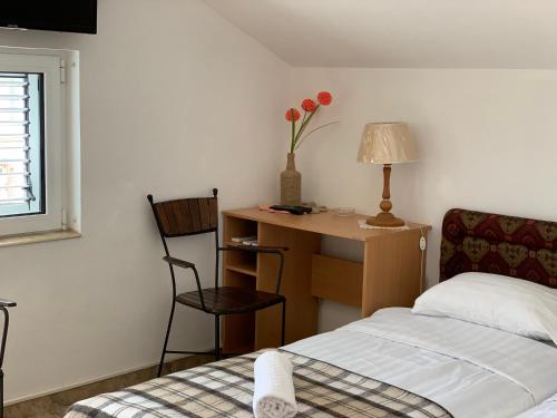 una camera con letto e scrivania con vaso di fiori di Zvezda Meljine a Herceg-Novi