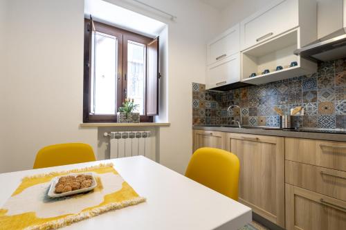 a kitchen with a white table and yellow chairs at Via Venezia 32 House in Petralia Sottana
