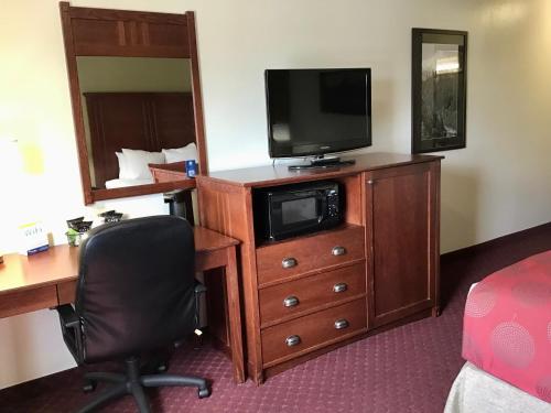 a hotel room with a desk and a television on a dresser at Baymont by Wyndham Bozeman in Bozeman