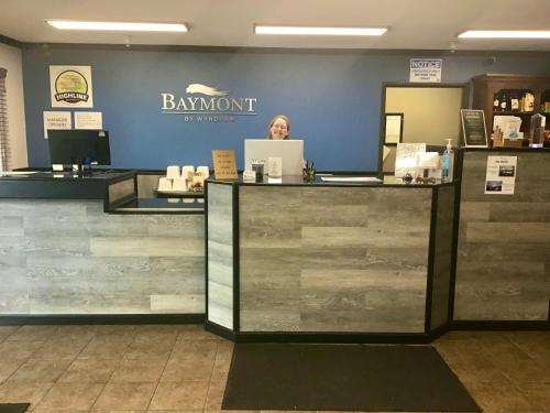 a woman standing at the counter of a bar at a barmont store at Baymont by Wyndham Bozeman in Bozeman