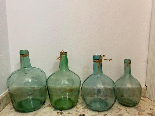 four green glass bottles sitting on a table at Alojamiento Armenia Piscina in Alcalá de los Gazules