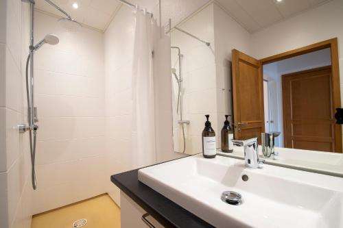 ein weißes Bad mit einem Waschbecken und einer Dusche in der Unterkunft Stylish two floor Deluxe Apartment - 2 bedroom in Sønderborg