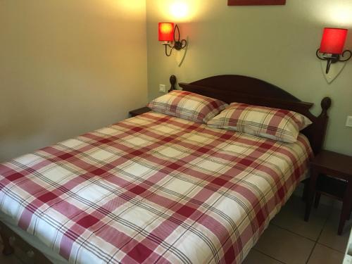 une chambre avec un lit avec une couverture à carreaux dans l'établissement Le Domaine de Gascogne - appartement 2 pièces 4/5 personnes, à Biscarrosse