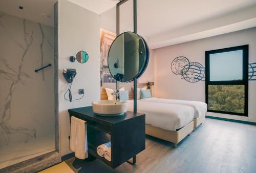 a bedroom with a bed and a sink and a mirror at Occidental Tanger in Tangier