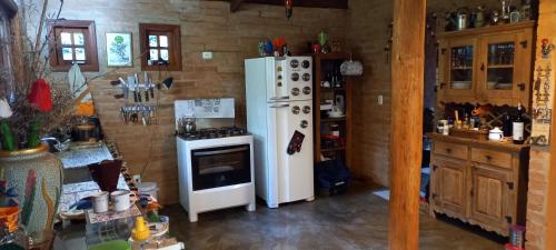 Il comprend une cuisine équipée d'un réfrigérateur blanc et d'une cuisinière. dans l'établissement CASA EM MONTE VERDE CHARME E CONFORTO, à Monte Verde