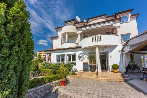 a large white house with a patio and trees at Apartments Villa Bare in Kastav