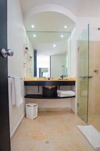 a bathroom with a shower and a sink and a mirror at Tamaca Beach Resort in Santa Marta