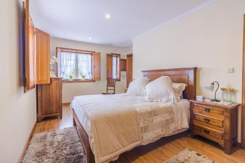 a bedroom with a large bed and a wooden dresser at Araújo 111 - Traditional House in Leça do Balio
