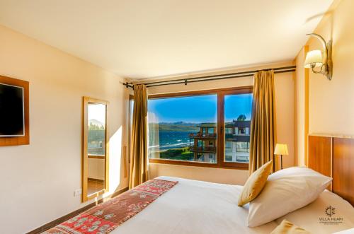 a bedroom with a bed and a large window at Villa Huapi in Dina Huapi