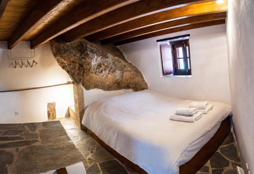 a bedroom with a bed with a rock on the wall at Kyklamino Castlehouse in Monemvasia