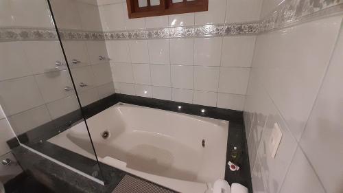 a bath tub in a bathroom with a glass wall at Jacuzzi Relax/Suíte climatizada/centro in Domingos Martins