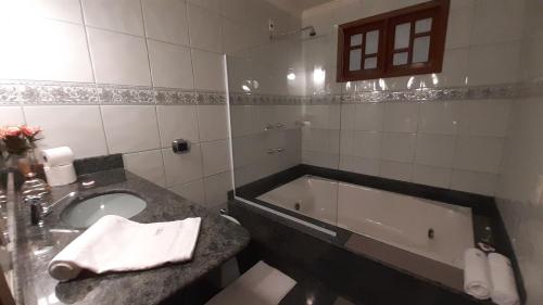 a bathroom with a sink and a bath tub at Jacuzzi Relax/Suíte climatizada/centro in Domingos Martins