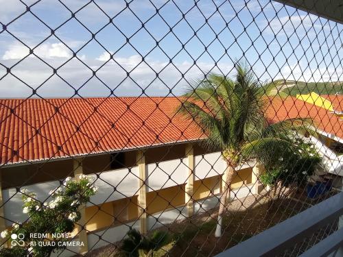 a building with a red roof with a palm tree at Village Hospedagens in Natal