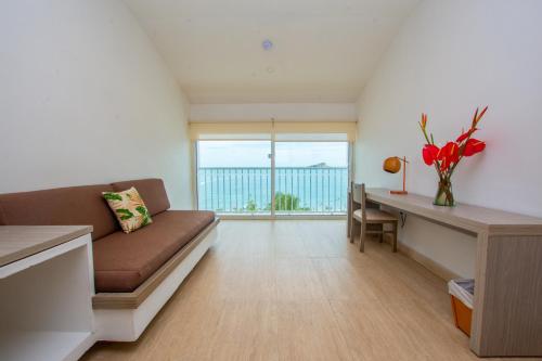 a living room with a couch and a table with a desk at Tamaca Beach Resort in Santa Marta