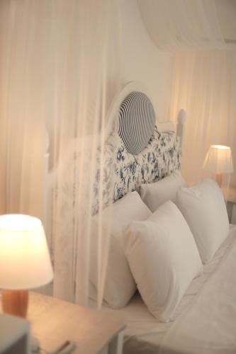 a white bed with white pillows and a fan at Mavi Konak Alaçatı in Alaçatı