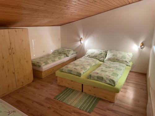 2 łóżka w niewielkim pokoju z drewnianą podłogą w obiekcie Apartmán ANNA w mieście Dúbrava