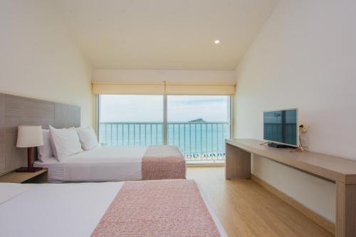 a bedroom with a bed and a view of the ocean at Tamaca Beach Resort in Santa Marta