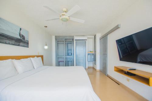 a bedroom with a white bed and a flat screen tv at Tamaca Beach Resort in Santa Marta
