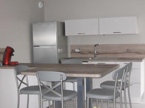 une cuisine avec une table avec des chaises et un réfrigérateur dans l'établissement Gîte de Romagers, à La Chaze-de-Peyre