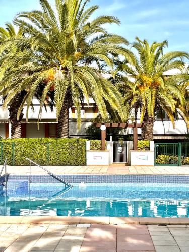 une piscine avec des palmiers devant un immeuble dans l'établissement L'Escapade Bohème, à La Grande Motte
