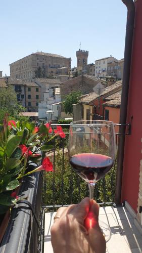 a person holding a glass of wine on a balcony at Aghèl Luxury Room in Recanati