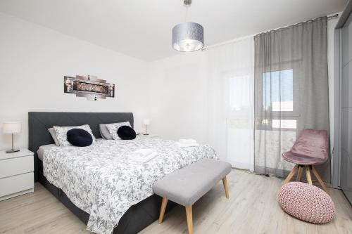 1 dormitorio blanco con 1 cama y 1 silla en Sweet City Center with balcony & private Parking en Pula