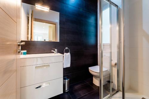 een badkamer met een toilet, een wastafel en een spiegel bij BARTOLOME Suite Apartment in San Sebastian